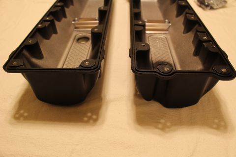 2003 Ford Crown Victoria - End-on view of two black valve covers showing their deep rails, gasket flanges and finned interior surfaces.