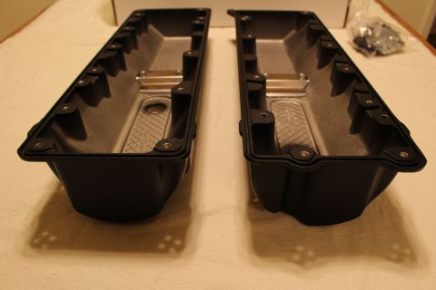 2003 Ford Crown Victoria - Two black valve covers shown end-on on a cloth, revealing finned interior baffles and sealing flanges.