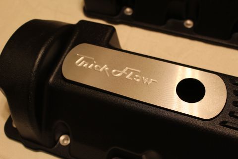 2003 Ford Crown Victoria - Tight close-up of a black valve cover's end cap and brushed aluminum plate engraved with the Trick Flow name beside an oil-fill hole.