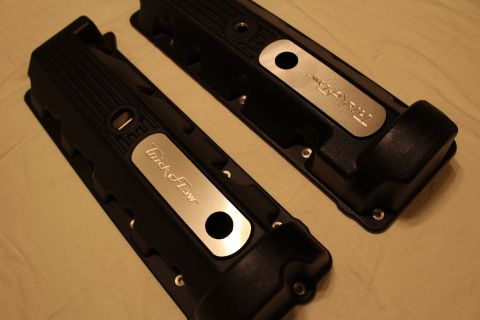 2003 Ford Crown Victoria - Two black engine valve covers with polished aluminum Trick Flow logo inserts laid on a tan cloth.