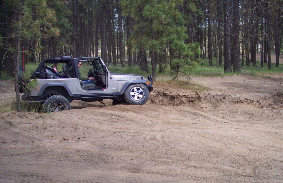 Silver 2005 Jeep Wrangler driving on dirt trail
