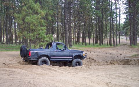 2005 Jeep Wrangler - A Ford Bronco navigates a sandy trail in a forest.