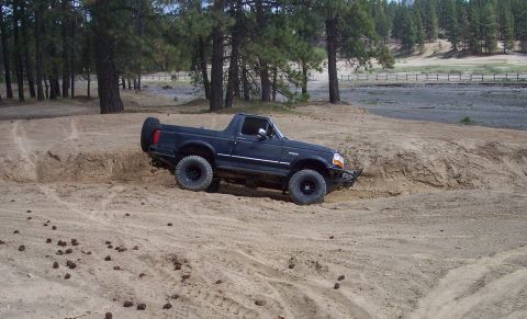 2005 Jeep Wrangler - This black Ford Bronco II is navigating a sandy off-road course.