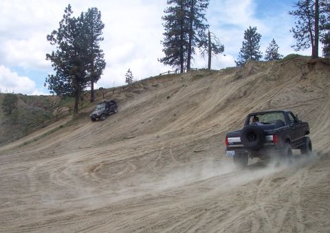 2005 Jeep Wrangler - Two 4x4 vehicles navigate a challenging sandy incline on an off-road trail.