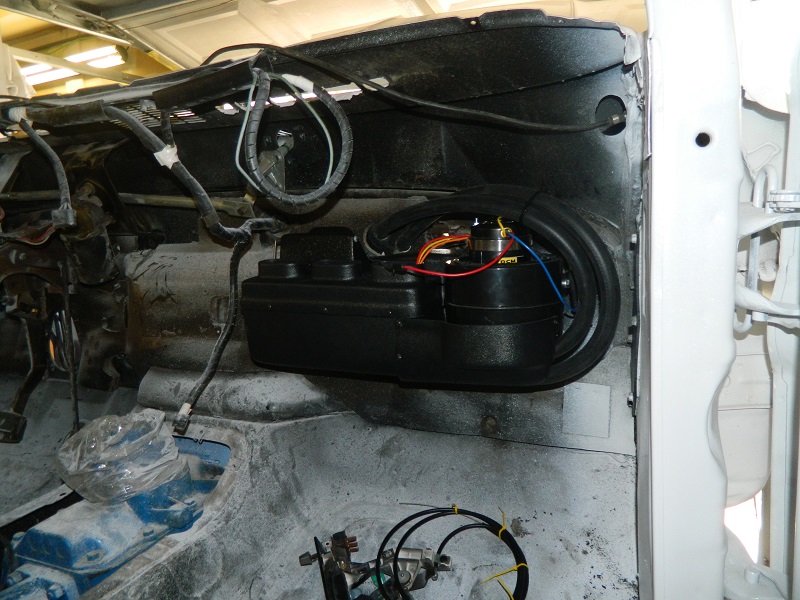 Close-up of a black A/C unit with wiring, installed in a vehicle's interior