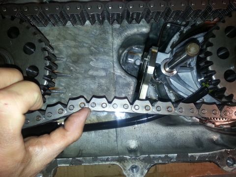 1995 Ford Bronco - A hand points to the internal components of a vehicle's transfer case, showing a chain and gears.