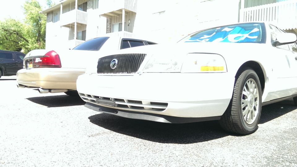 Front view of a white Mercury Grand Marquis and a tan Ford Crown Victoria parked side-by-side