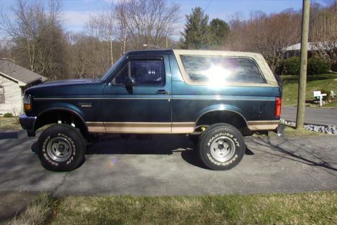 1995 Ford Bronco - Side view of a lifted 1995 Ford Bronco with aftermarket wheels and tan trim.
