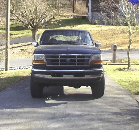 1995 Ford Bronco - This Ford F-150 pickup truck is shown from the front, parked in a driveway with a house and trees in the background.