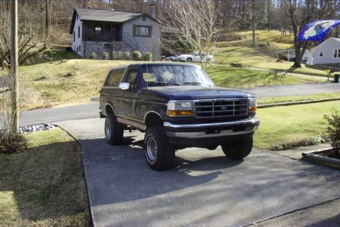 1995 Ford Bronco - This lifted 1995 Ford Bronco is parked on a concrete driveway in front of a house.