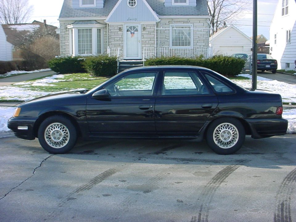 Black four-door sedan in side profile parked on a residential street