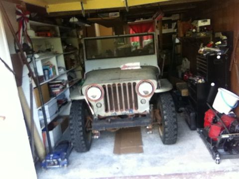1946 Jeep CJ5 - This Jeep, likely from the 1940s, is parked in a cluttered garage with shelves and tools.