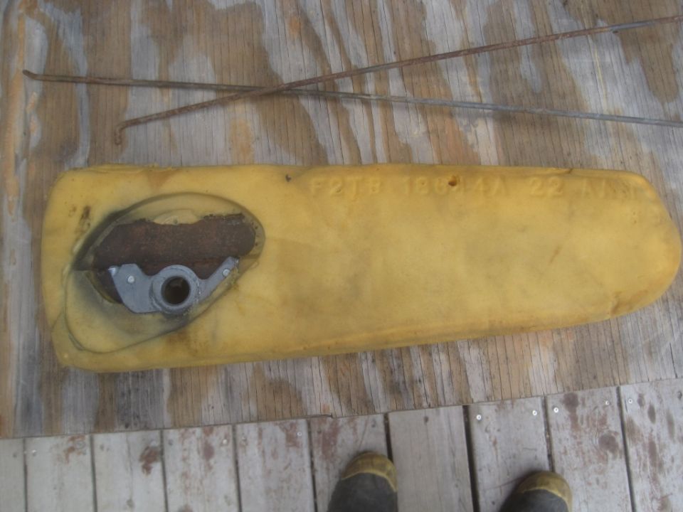 Yellow foam part with metal mechanism and rusty wires, text 'F2TB 19G44 AA 22A' visible