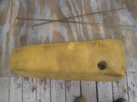 1993 Ford Bronco - Yellow foam padding with a hole, possibly a seat cushion, rests on a wooden surface next to two rusty metal rods.