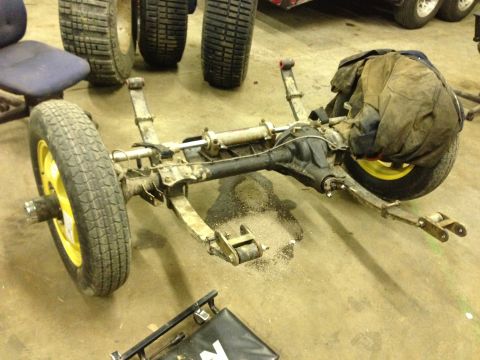1999 Isuzu Vehicross - A disassembled vehicle axle assembly sits on a concrete floor, showing suspension components and a wheel.