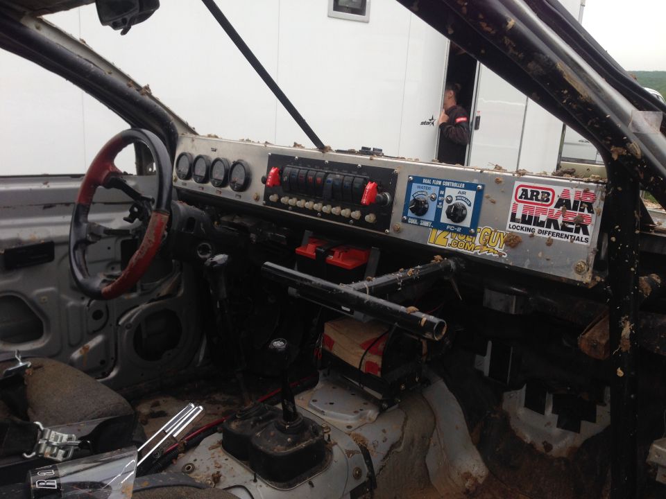 Custom dashboard with gauges, switches, and ARB Air Locker stickers. Roll cage visible