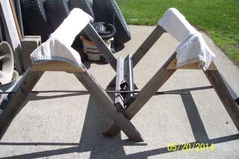 1990 Ford Bronco - A wooden sawhorse is set up outdoors, with towels placed on its supports and a bucket and tires visible behind it.