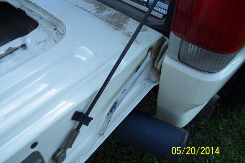 1990 Ford Bronco - Close-up of the tailgate torsion bar mechanism on a white 1990 Ford Bronco.