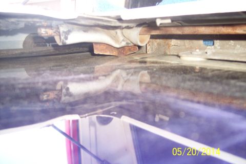 1990 Ford Bronco - Close-up view of a rusty tailgate torsion bar mechanism, showing metal brackets and rods.