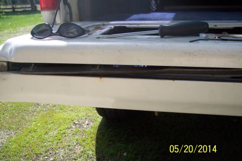 1990 Ford Bronco - Close-up of the tailgate torsion bar mechanism on a 1990 Ford Bronco, with sunglasses and a screwdriver resting on the surface.