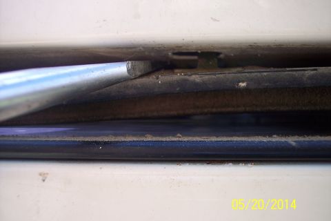 1990 Ford Bronco - Detail of the tailgate torsion bar mechanism, showing the metal rod and surrounding components.