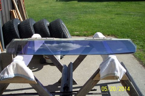 1990 Ford Bronco - A windshield is propped up on sawhorses outdoors, with a stack of tires visible behind it.