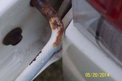 1990 Ford Bronco - Close-up of a rusted torsion bar hinge on a white vehicle component, with a Supermotors.net watermark.
