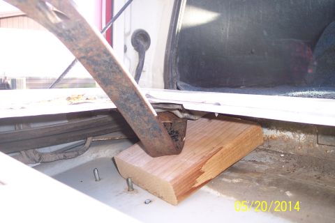 1990 Ford Bronco - A wooden block supports the tailgate torsion bar mechanism within the cargo area of a vehicle.