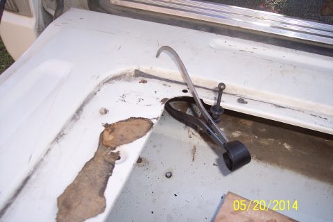 1990 Ford Bronco - Close-up of a tailgate torsion bar mechanism, showing wear and rust on the surrounding metal.