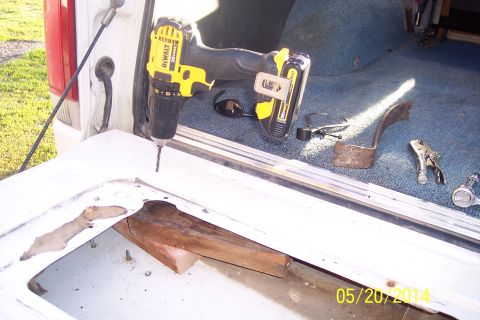 1990 Ford Bronco - Drilling into the tailgate interior of a 1990 Ford Bronco, with tools and sunglasses nearby.