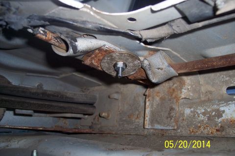 1990 Ford Bronco - Undercarriage view of a rusted torsion bar with a bolt and washer attached.