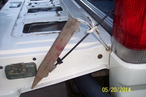 1990 Ford Bronco - The tailgate torsion bar mechanism on a 1990 Ford Bronco, showing a wooden brace used for support.