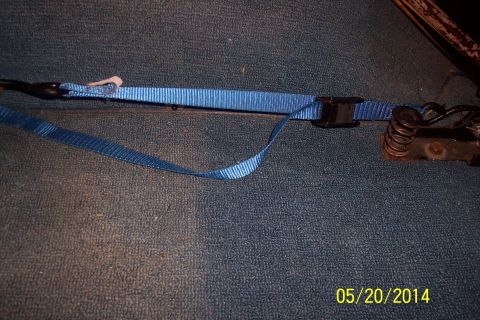 1990 Ford Bronco - Close-up of a blue strap connected to a tailgate torsion bar mechanism, showing a spring.