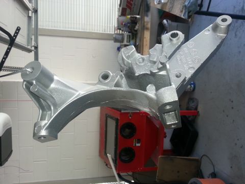 1994 Ford Bronco - A silver engine part, marked with a Ford logo, is shown suspended in front of a red sandblasting cabinet.