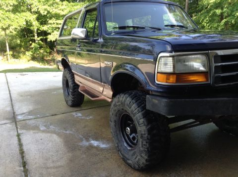 1995 Ford Bronco - This Ford Bronco is shown from the front three-quarter view, highlighting its lifted suspension and off-road tires.