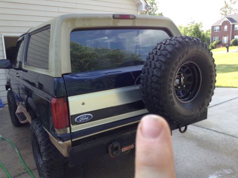 1995 Ford Bronco - Rear view of a 1995 Ford Bronco, a spare tire mounted externally and the iconic Ford badge on the tailgate.