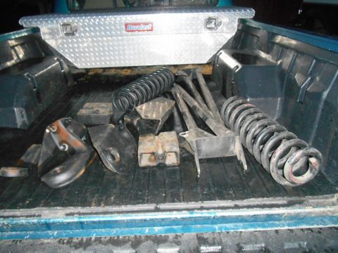 1994 Ford Bronco - Various suspension components are laid out in the bed of a pickup truck next to a toolbox.