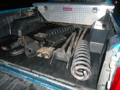 1994 Ford Bronco - Suspension lift kit components are stored in the bed of a pickup truck.