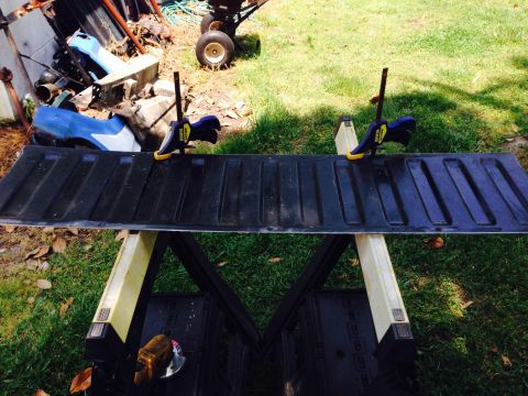 1979 Ford Bronco - Tailgate clamped to sawhorses for work, with yard debris and a trailer in the background.