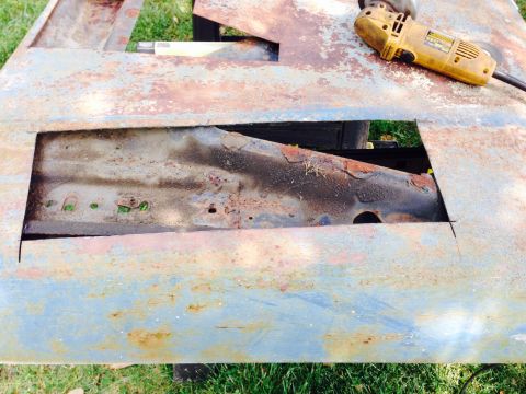 1979 Ford Bronco - A heavily rusted metal panel, possibly a car part, is being worked on with an angle grinder.