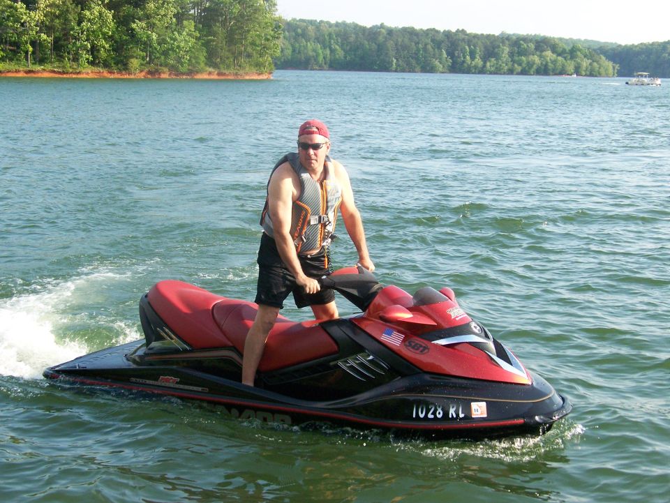 Man riding a red and black 2006 Sea-Doo 230 Wake jet ski on a lake