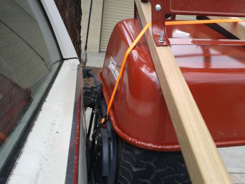 1990 Ford Bronco - A red wheelbarrow is strapped to the side of a white vehicle.