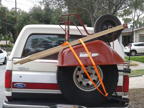 1990 Ford Bronco - A white Ford Bronco is seen from the rear, carrying a red wheelbarrow and a spare tire.