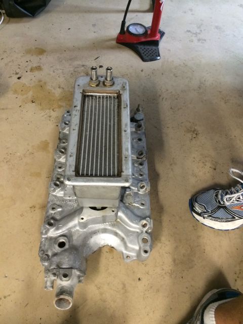 1996 Ford Bronco - An aluminum supercharger manifold with an intercooler is shown on a concrete floor next to a shoe and tire pump.