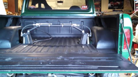 1967 Ford F-250 - The bed of a green Ford pickup truck is shown with custom suspension components installed.