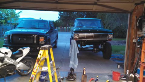 1967 Ford F-250 - A green 1967 Ford F-250 pickup truck is parked in a garage next to a newer black pickup truck and a motorcycle.