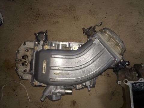 1996 Ford Bronco - This is a close-up view of an engine intake manifold, likely removed from a vehicle for repair or replacement.