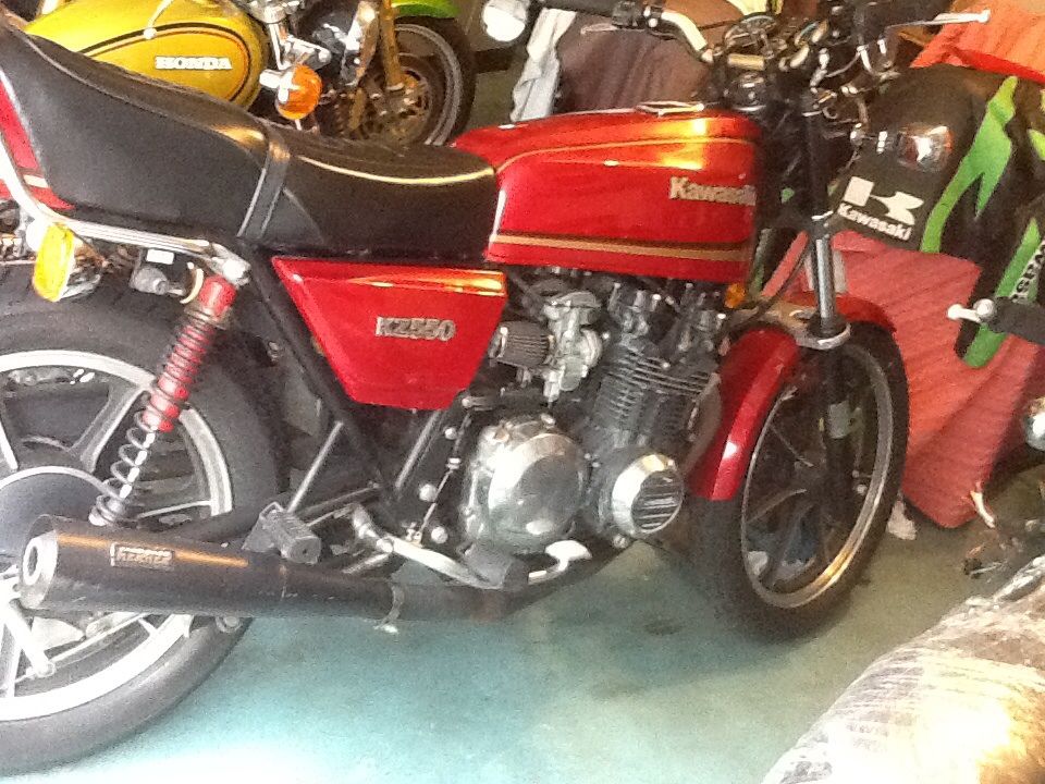Red Kawasaki KZ550 motorcycle side view. Other motorcycles visible