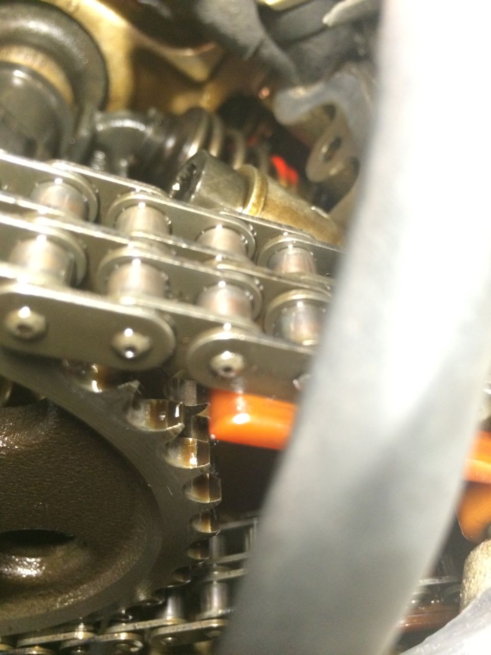 Close-up of engine timing chain and gears with orange plastic guide