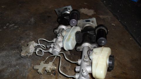 1972 Ford Ranchero - Multiple brake master cylinders are laid out on a dark, textured surface, showing various components and reservoirs.